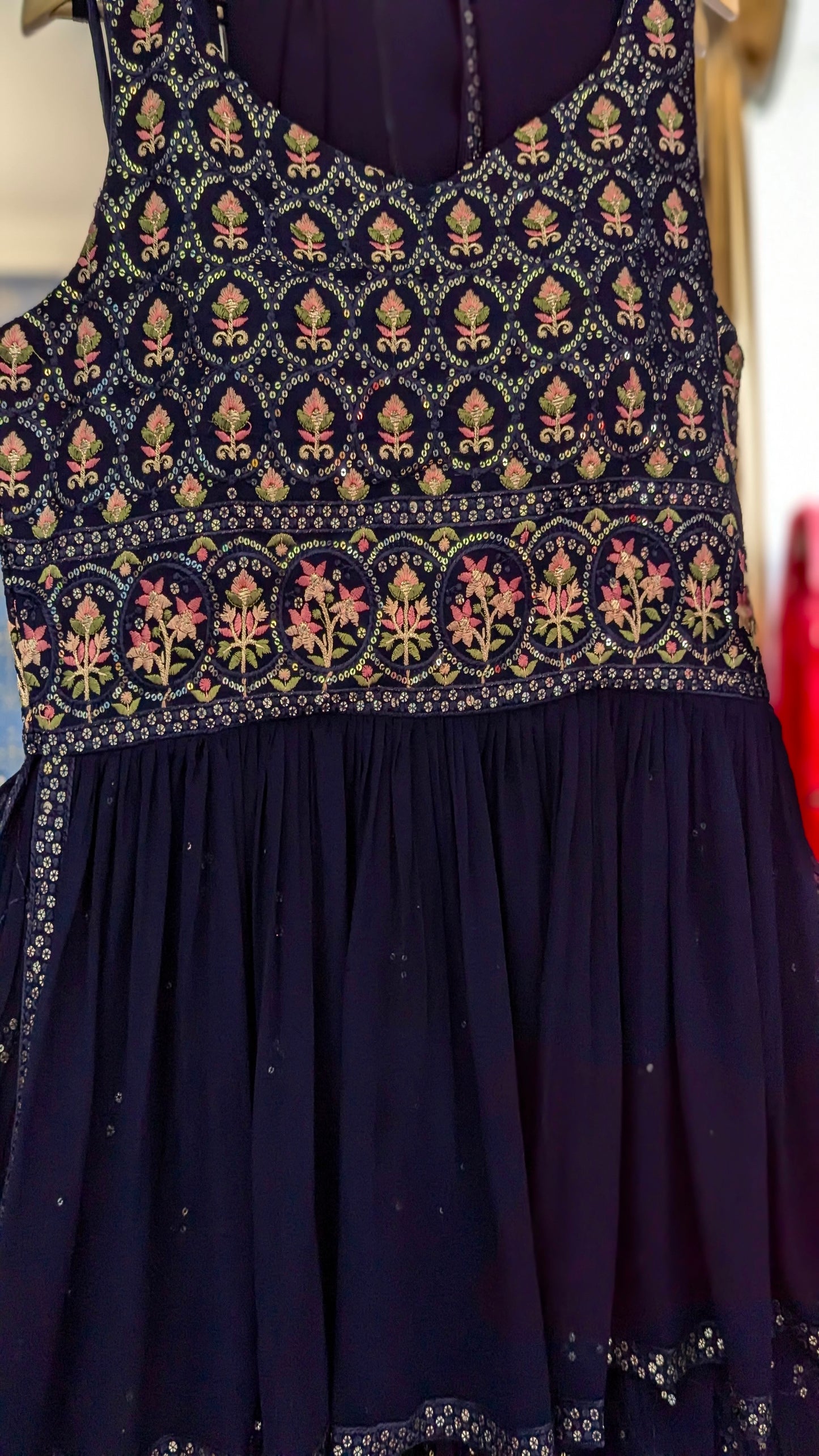 Navy blue peplum sharara with gold and threadwork floral embroidery on a hanger against a mirror background