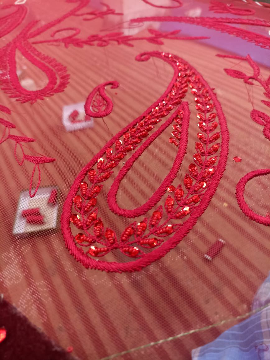 Sherni London red net fabric hand embroidery in progress with thread spools sequins threadwork and beads
