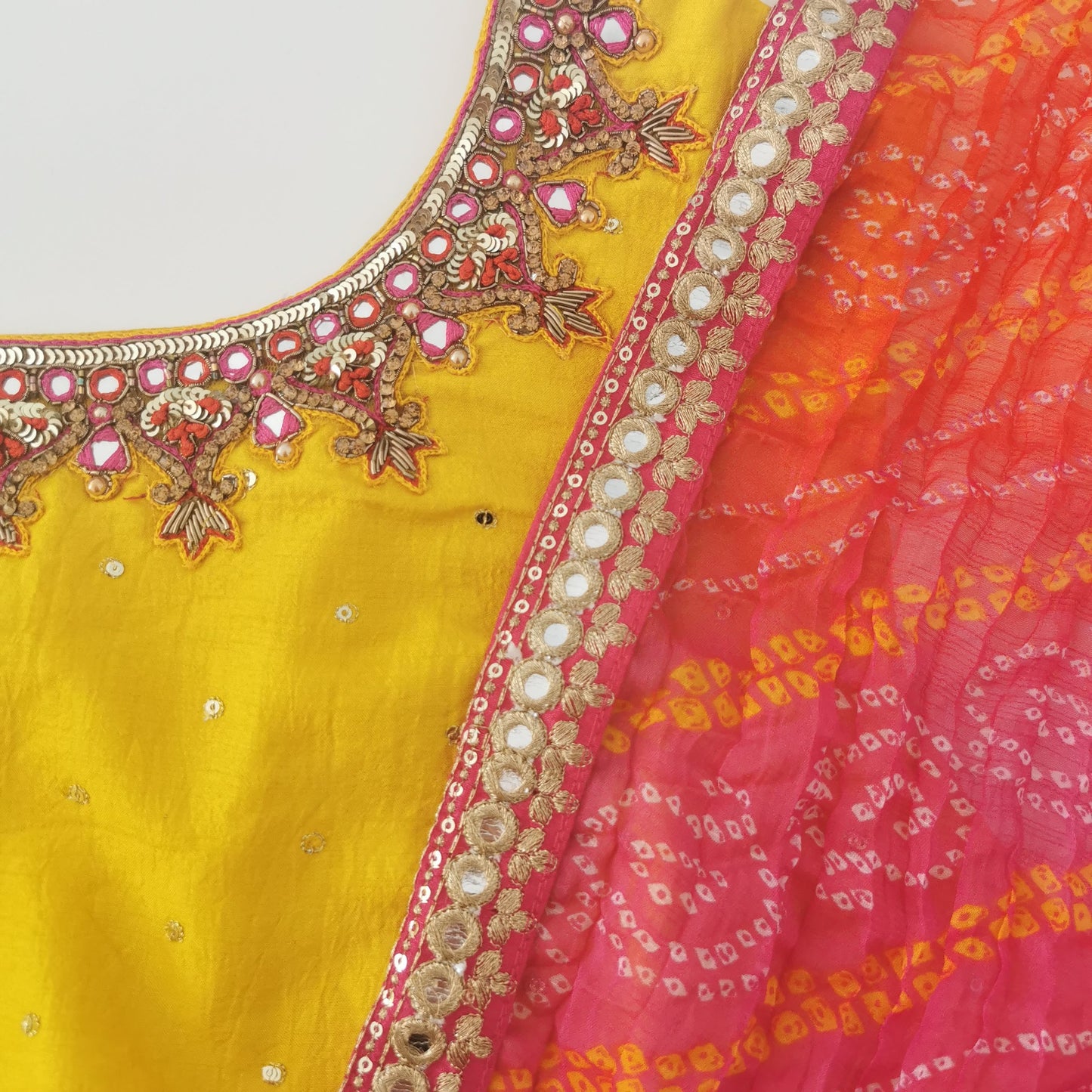 yellow gown with sequins all over and hand embroidered neckline with pink red and orange bandhani dupatta