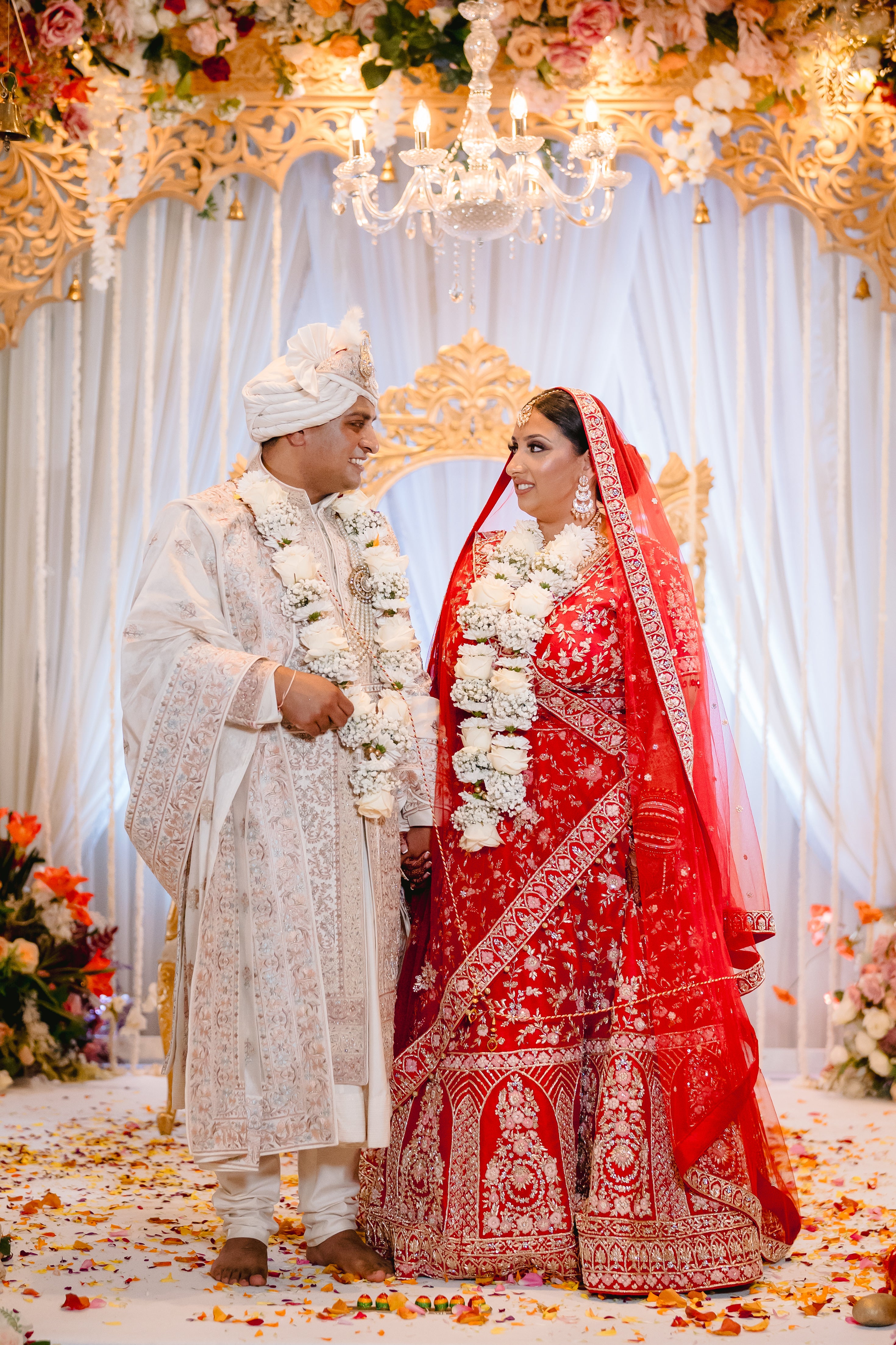 Sherni London real Indian bride and groom in cream sherwani and red lehenga and two dupattas, gold embroidery and multicoloured threadwork