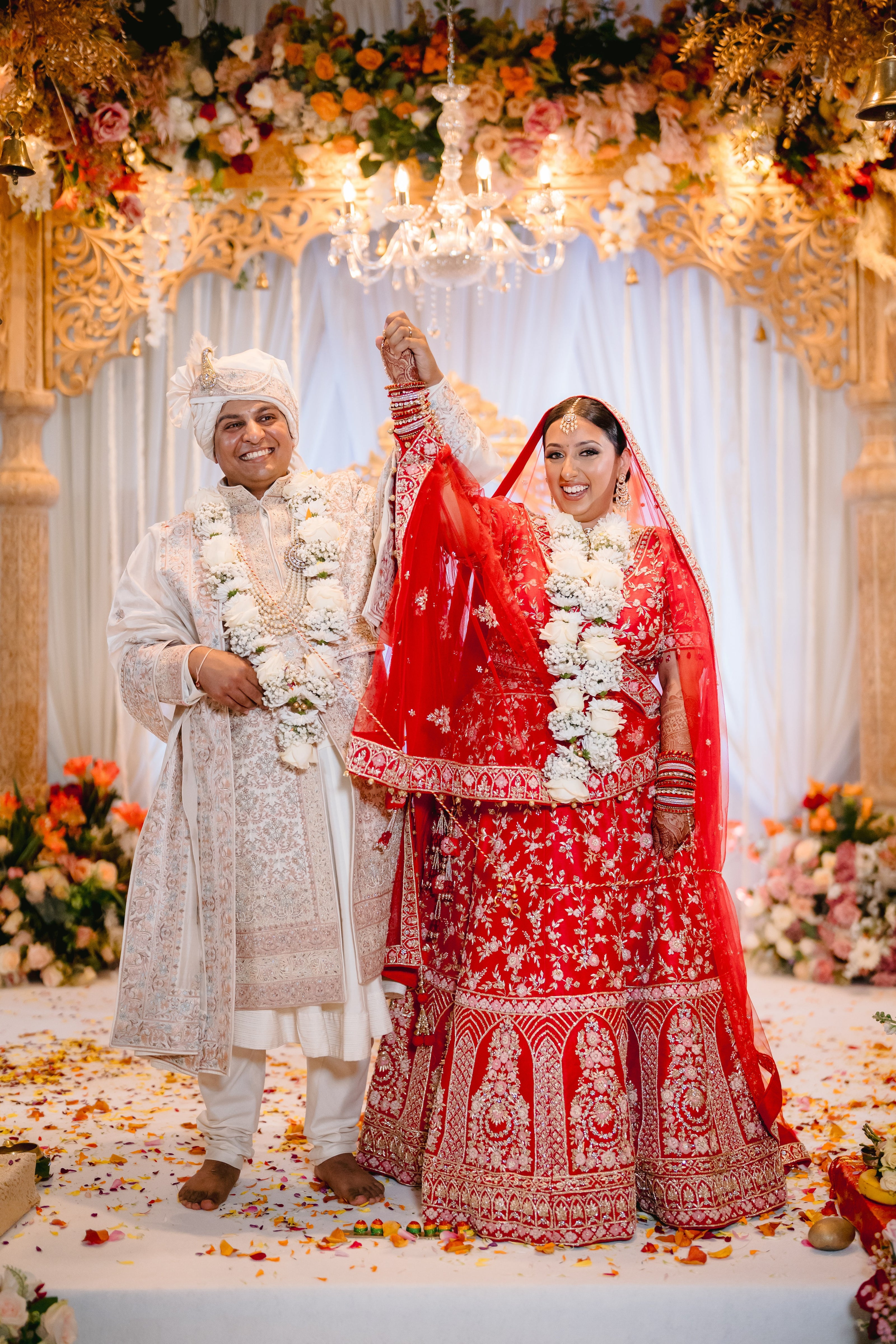 Sherni London real Indian bride and groom in red lehenga cream sherwani and two dupattas, gold embroidery and multicoloured threadwork