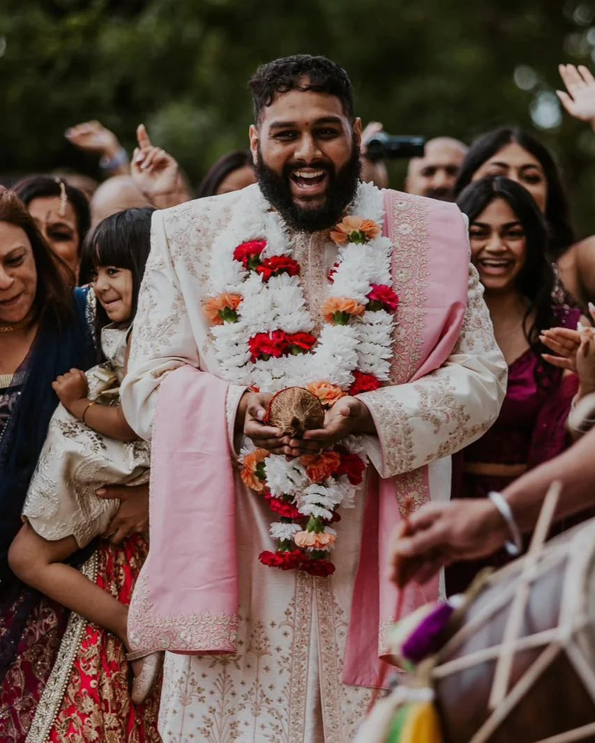 Sherni London groom in bespoke traditional Indian sherwani in cream with pink dupatta and gold embroidery