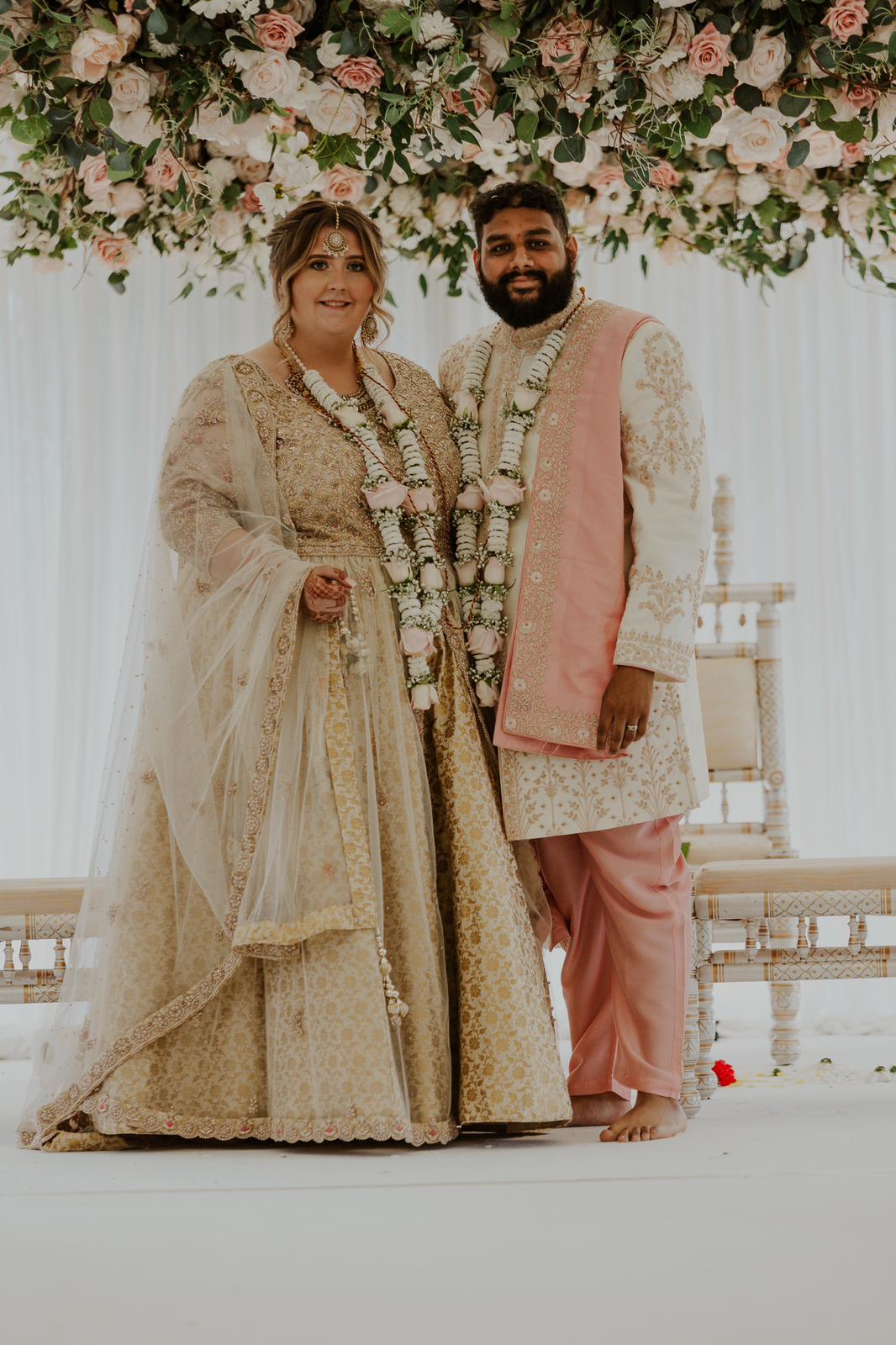 Sherni London fusion bride and groom in cream indian lehenga and cream and pink sherwani at Hindu wedding ceremony