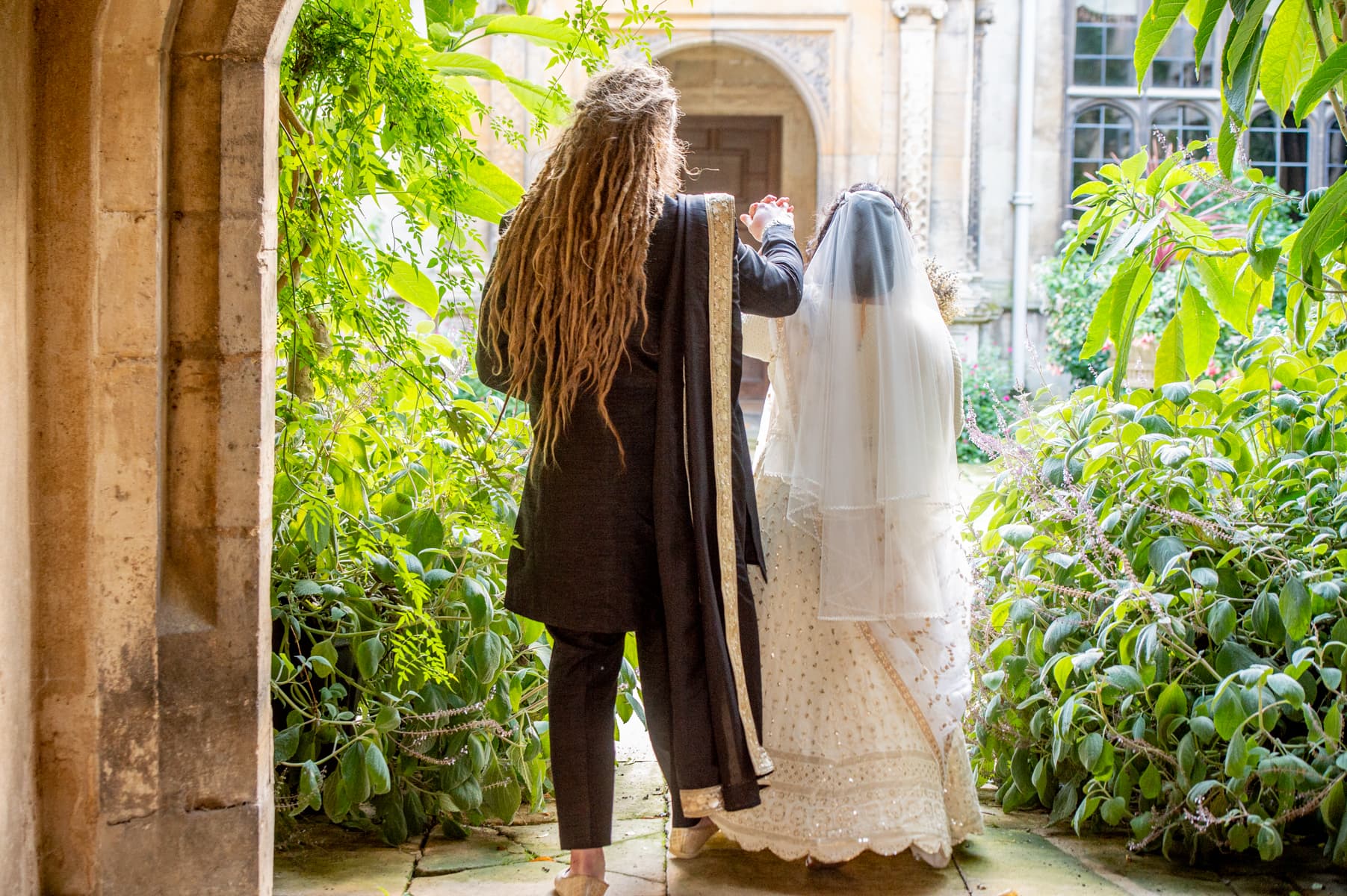 Sherni London bride and groom in fusion church wedding ceremony wearing white chikankari lucknowi lehenga and black asymmetric sherwani with gold buttons and trim