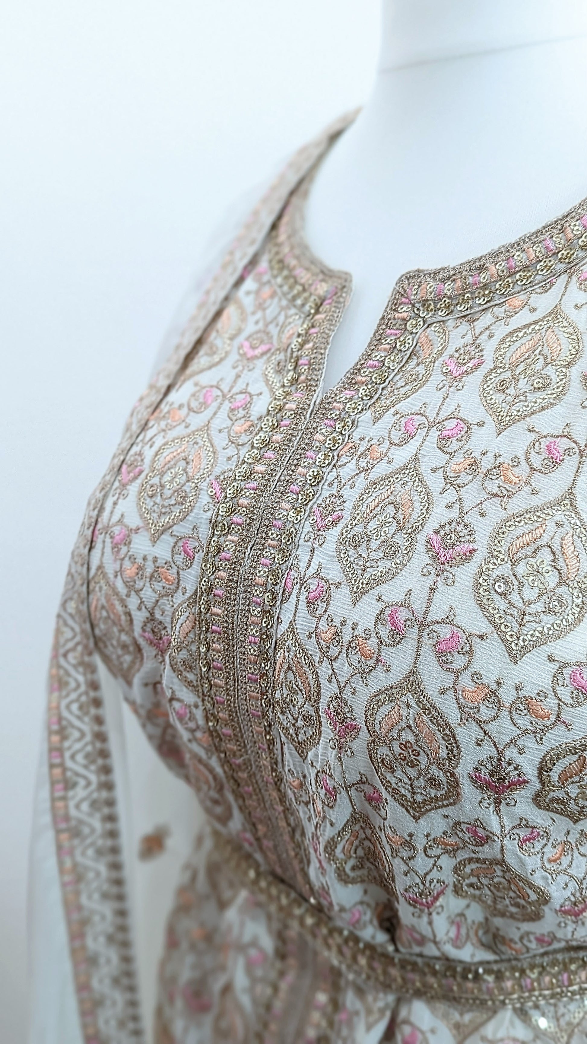 Mannequin wearing a cream jacket sharara suit set with sequins hand embroidery and threadwork long sleeves belt and dupatta