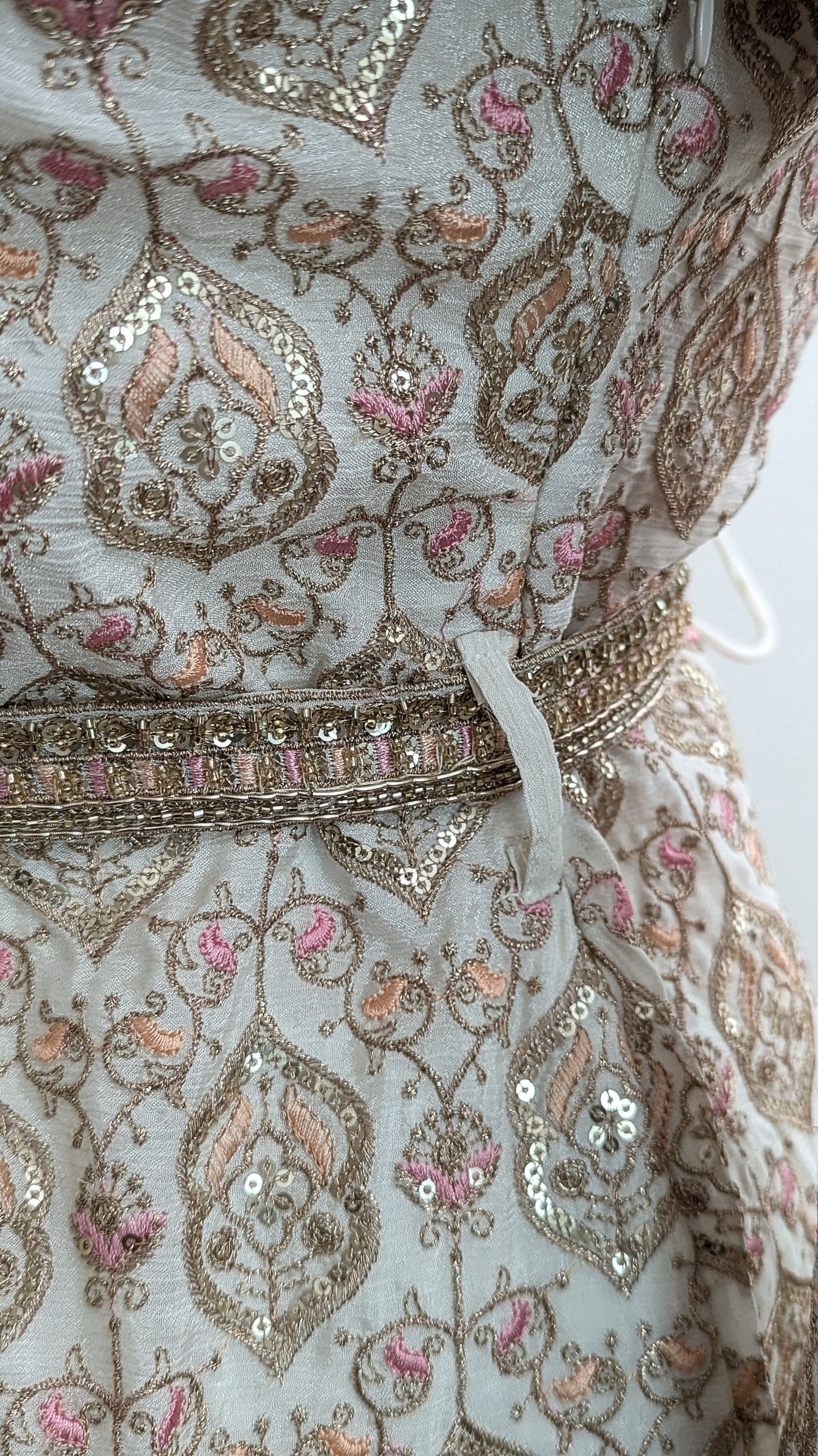 Mannequin wearing a cream jacket sharara suit set with sequins hand embroidery and threadwork long sleeves belt and dupatta