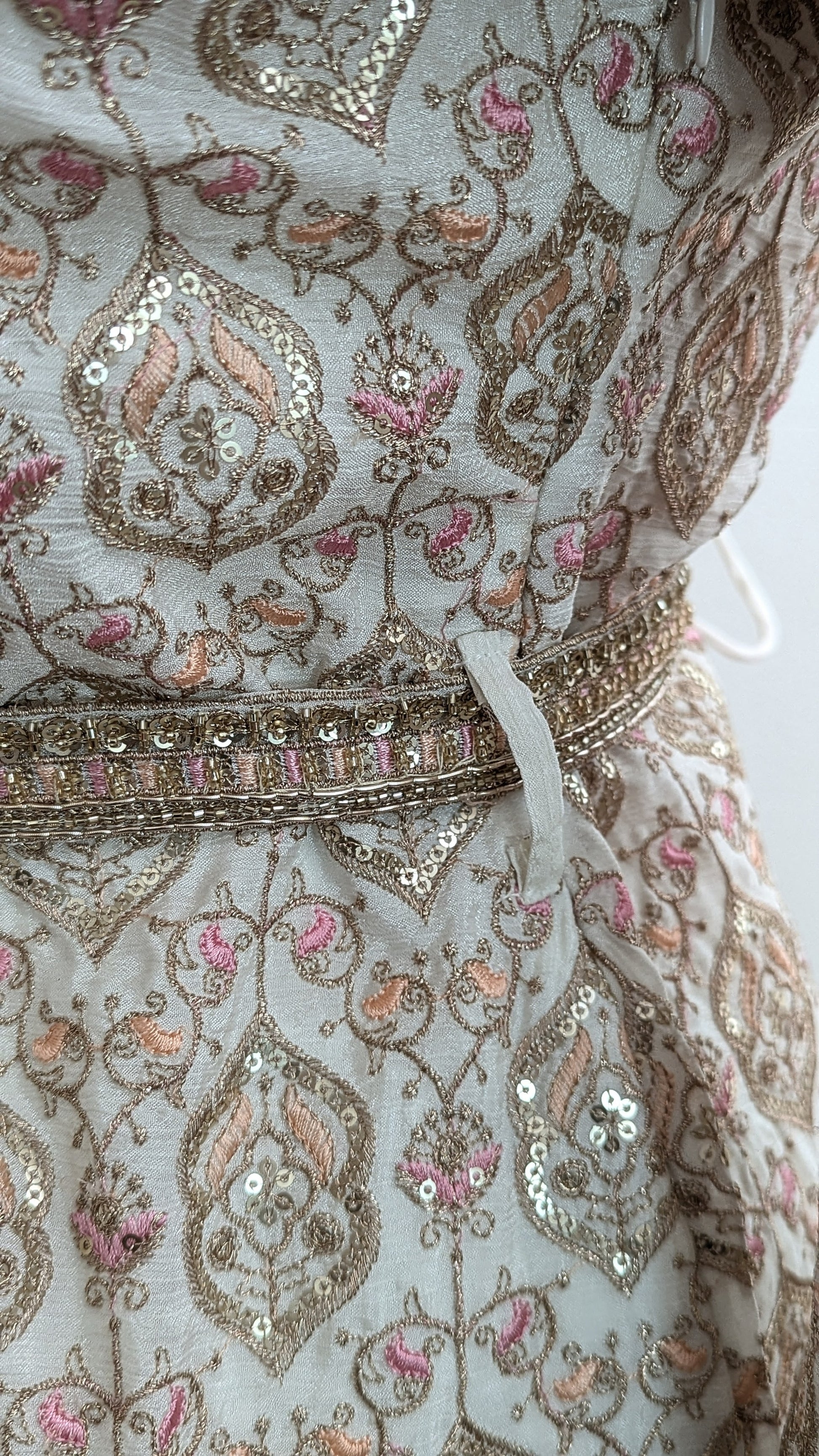 Mannequin wearing a cream jacket sharara suit set with sequins hand embroidery and threadwork long sleeves belt and dupatta