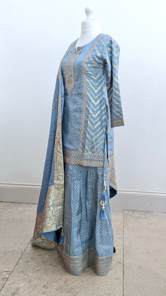 Mannequin with traditional gharara suit in blue grey with gold benarsi print and chevron design all over with sleeves and side tassels