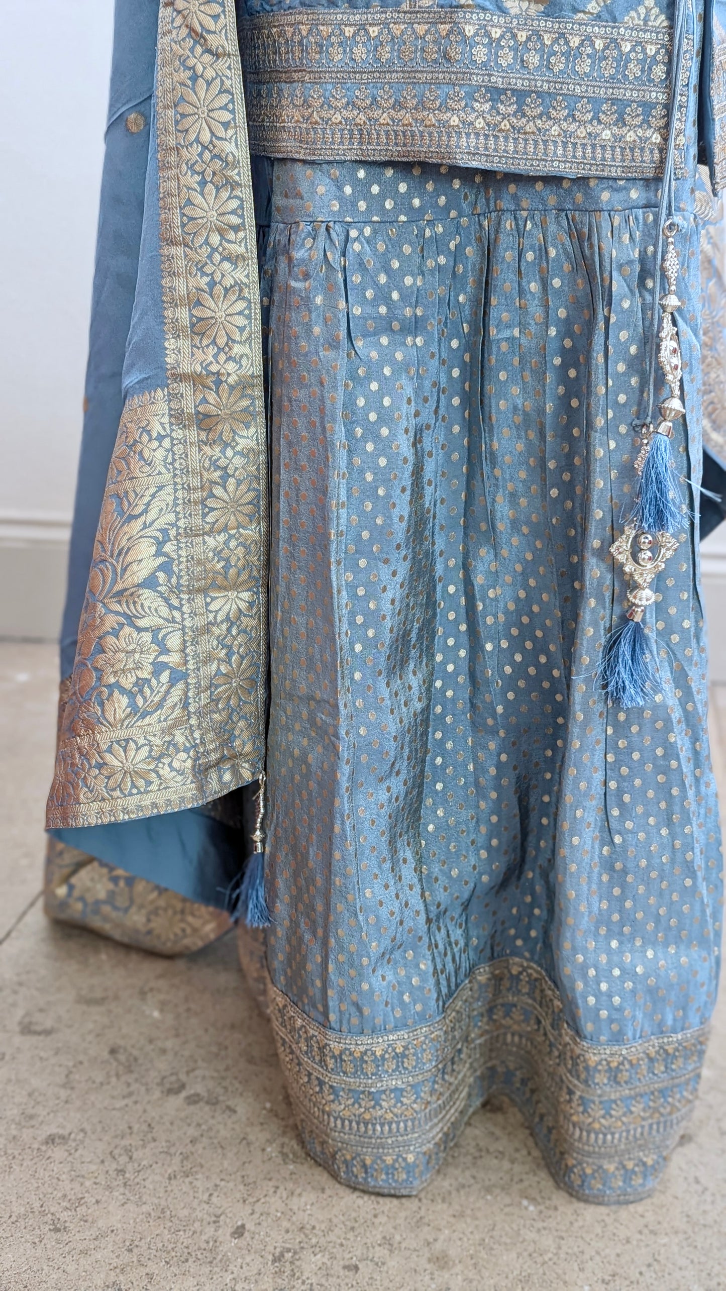 Mannequin with traditional gharara suit in blue grey with gold benarsi print and chevron design all over with sleeves and side tassels