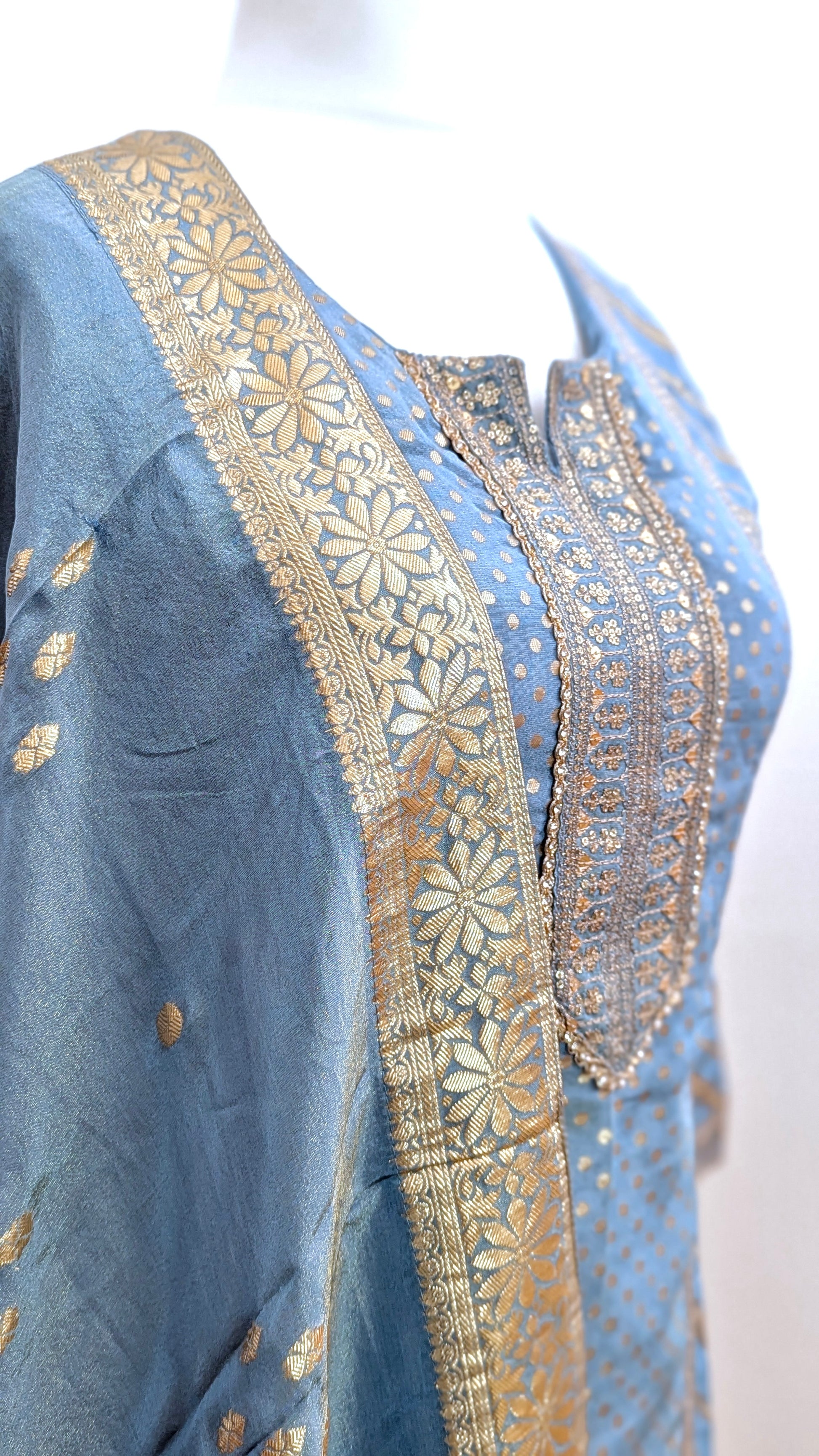 Mannequin with traditional gharara suit in blue grey with gold benarsi print and chevron design all over with sleeves and side tassels
