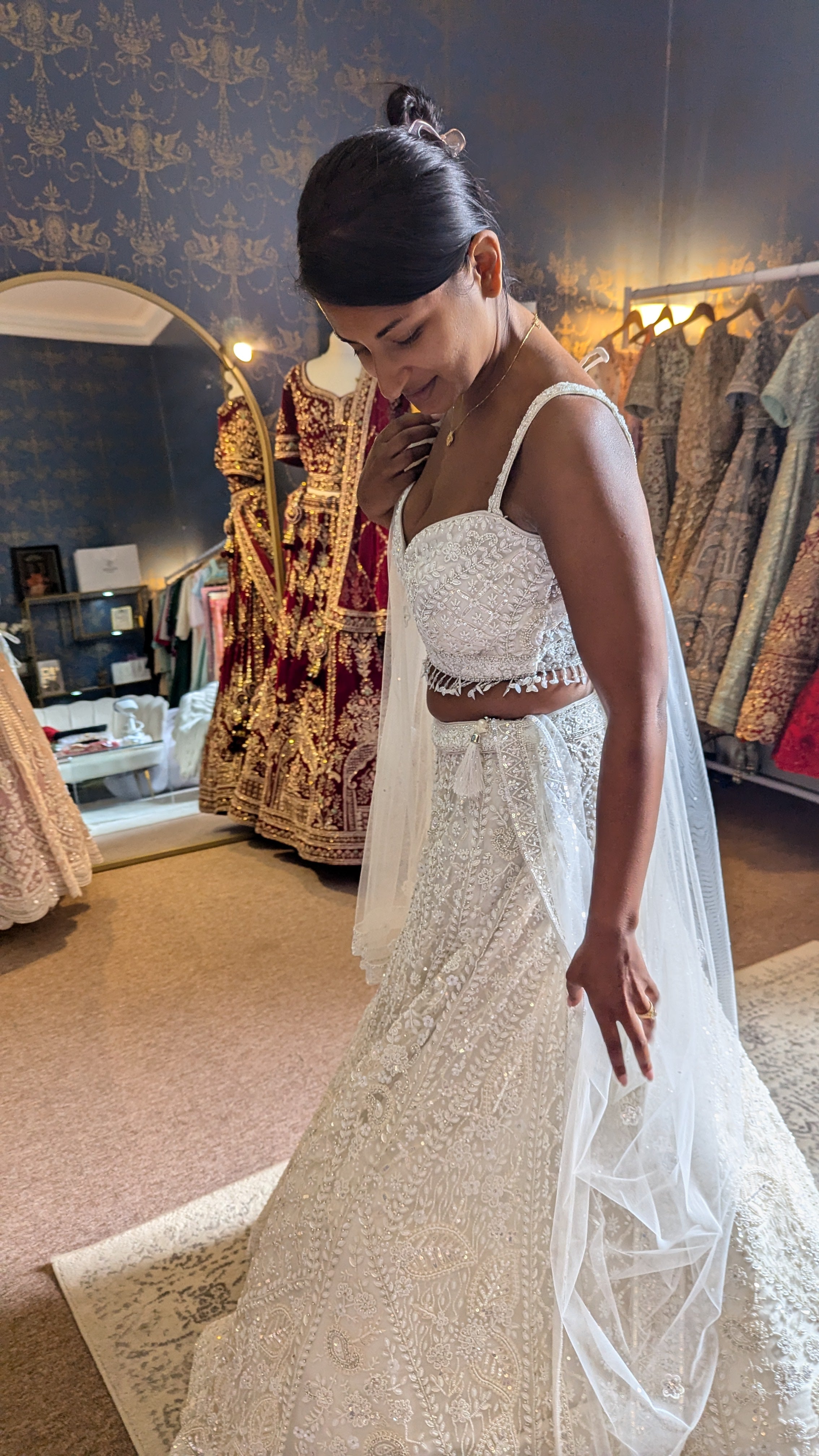 Bride in white hand embroidered lehenga standing in the Sherni London boutique for her lehenga fitting
