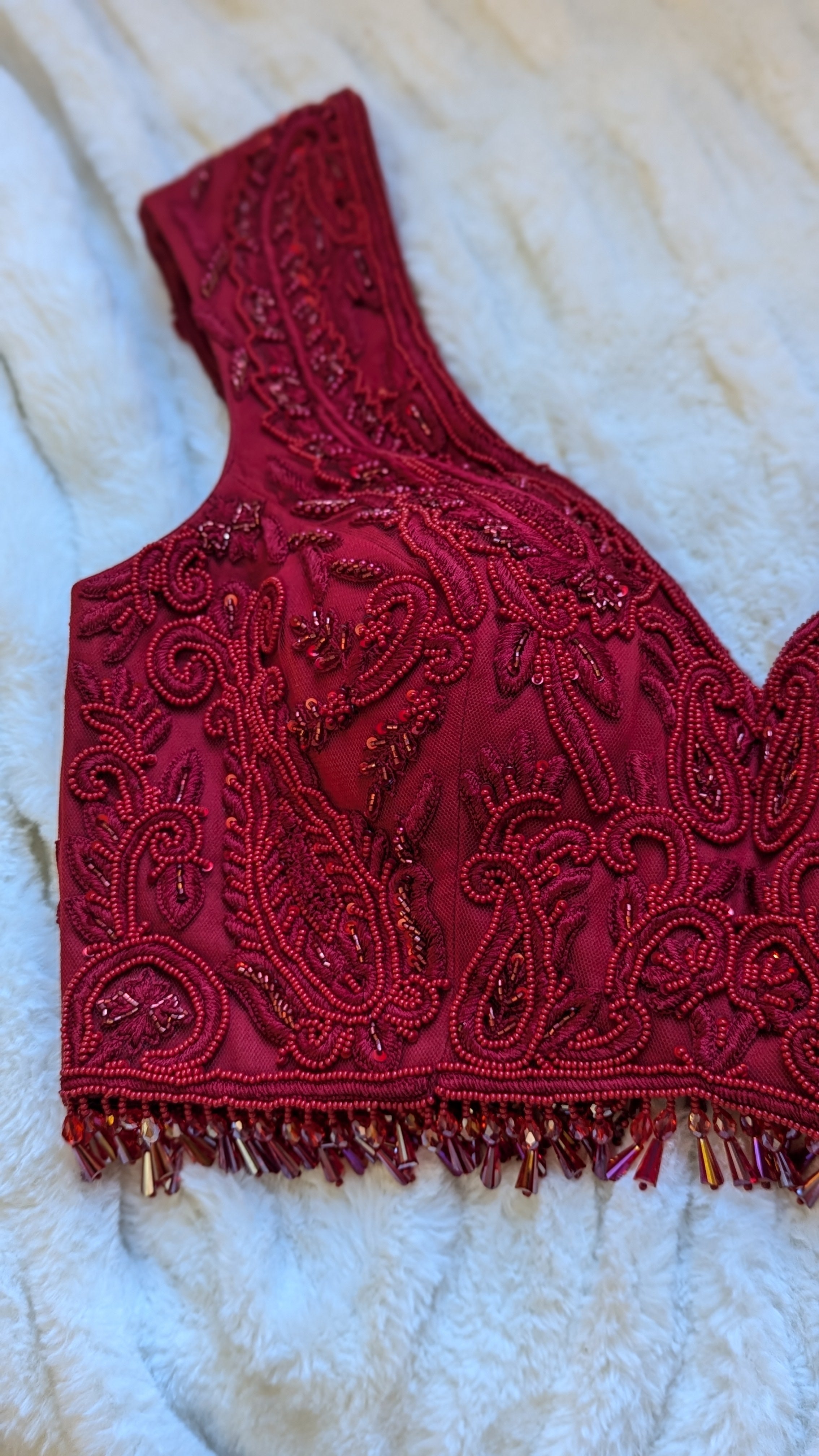 Red hand embroidered lehenga top choli with bead droplets close up photo
