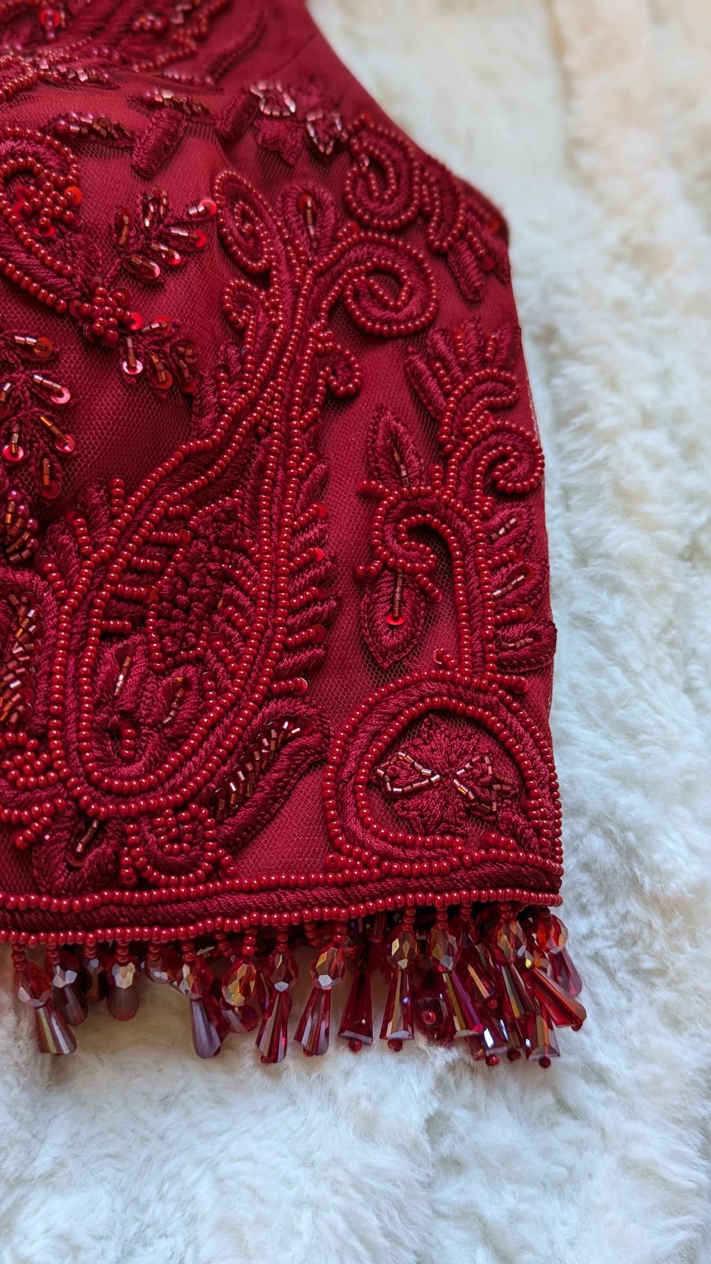 Red hand embroidered lehenga top choli with bead droplets close up photo
